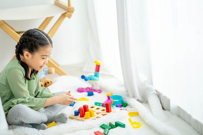 Side view of girl playing with toy at home