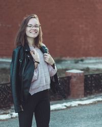 Portrait of smiling young woman standing on road