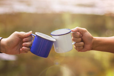 Cropped image of hands toasting coffee cup