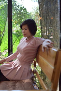 Woman looking through tree trunk