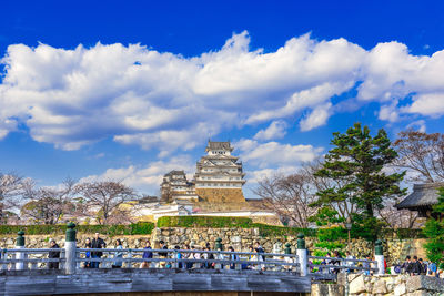 Group of people in temple against cloudy sky