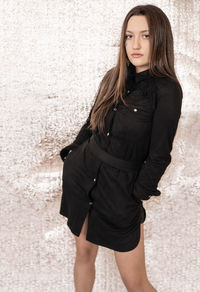 Portrait of a beautiful young woman standing against wall