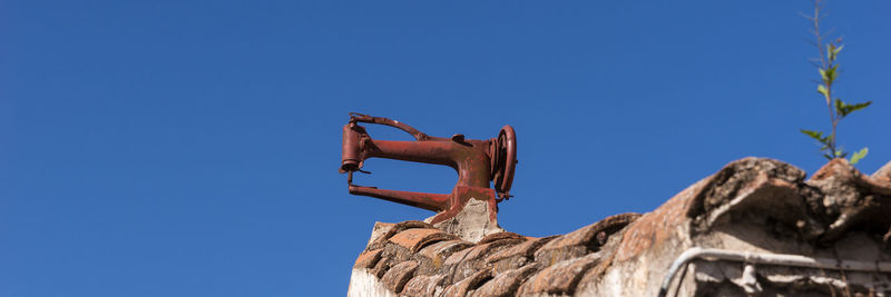 Low angle view of rusty metal against clear blue sky