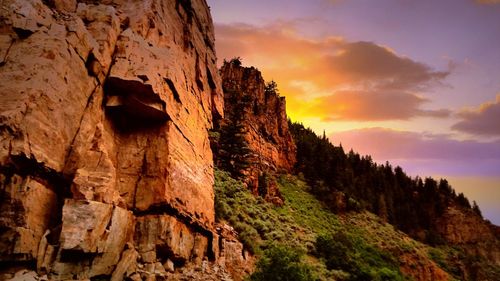 Low angle view of cliff against sky during sunset