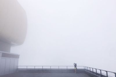 Man standing on bridge against sky