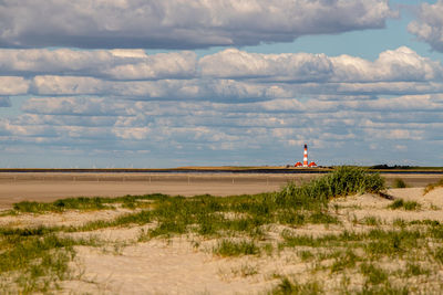 Lighthouse by sea against sky