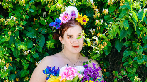 Portrait of young woman standing against plants