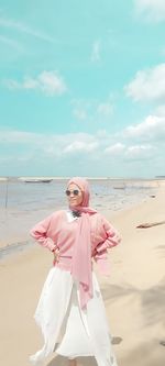 Woman with umbrella on beach against sky
