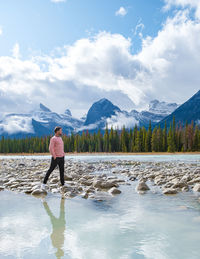 Rear view of woman standing by lake against sky