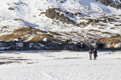 Rear view of people walking on snow covered mountain