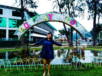 Full length portrait of smiling woman standing in rain