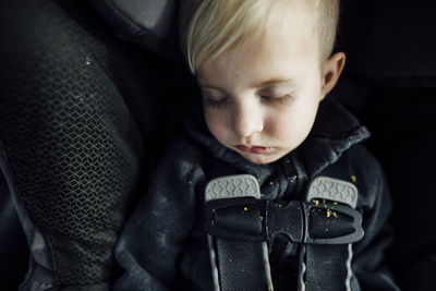 High angle view of cute boy sleeping on vehicle seat in car