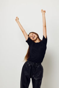 Cheerful girl with arms raised against white background