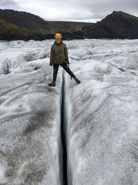 Rear view of man standing on snow covered mountain