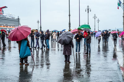 People on wet umbrella against sky in rain