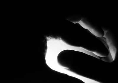 Close-up of silhouette hand against black background