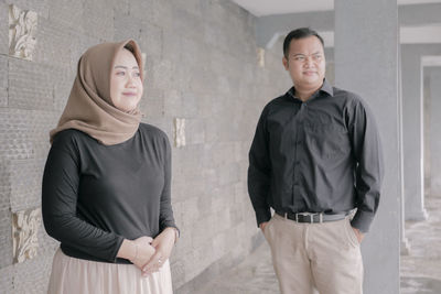 Full length of a young woman standing against wall