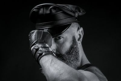 Portrait of man wearing cap against black background