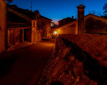 Illuminated alley amidst buildings in city at night