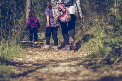 Mother and her two young daughters hiking in the woods on a cold autumn day in a red coat. 