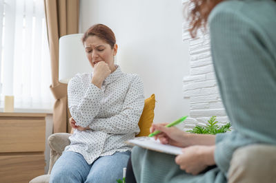 Young woman using phone while sitting on sofa at home