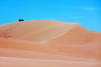 Sand dune in desert against blue sky