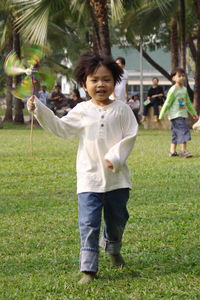 Full length of boy holding pinwheel while walking on field