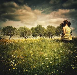 Trees on field against cloudy sky