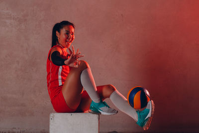 Full length of woman sitting with toy against wall