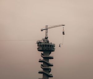 Crane at construction site against sky during sunset