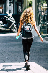 Rear view of woman walking on footpath in city