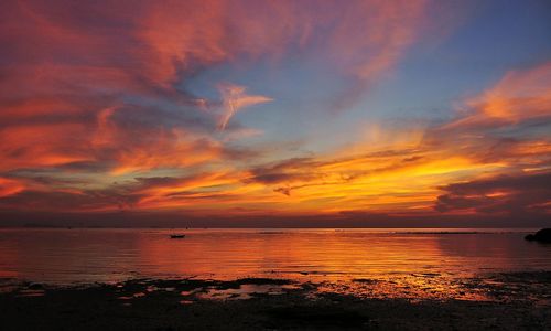 Scenic view of sea against dramatic sky during sunset