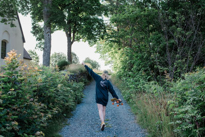 Woman dancing in a country lane with her skateboard in summer