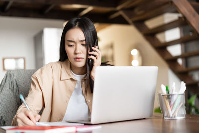 Young businesswoman using laptop at table