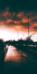 Street amidst silhouette trees against sky during sunset