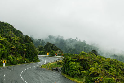 Road amidst trees against sky during rainy season