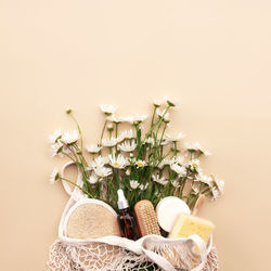 Beige background with eco shopping bag, chamomile flowers, bath accessories, essential oil, soap