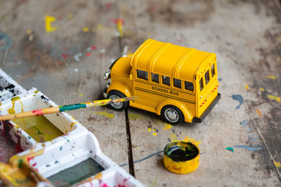 High angle view of yellow toy car and paintbrushes on table