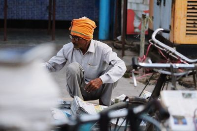 Rear view of man riding newspaper bicycle on street