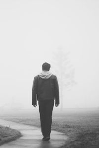 Rear view of man walking on field
