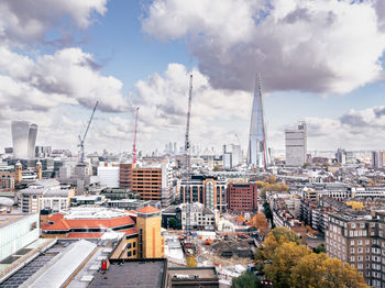 London skyline with shard and cranes, cityscape against cloudy sky