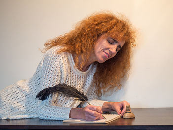 Woman looking away while sitting on table