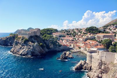 Panoramic view of sea and buildings against blue sky