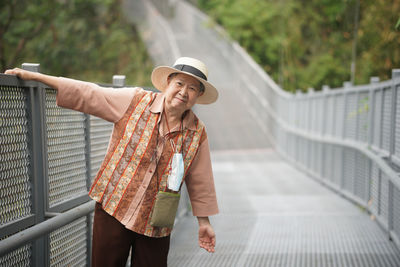 Portrait of woman standing against railing