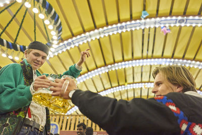 Friends drinking beer at illuminated amusement park