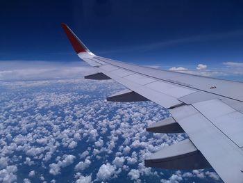 Airplane flying over clouds against blue sky