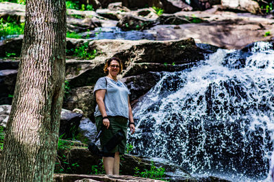 Low angle portrait of hiker standing against glendale falls in forest