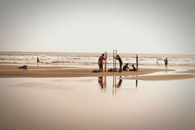 People playing on beach against clear sky