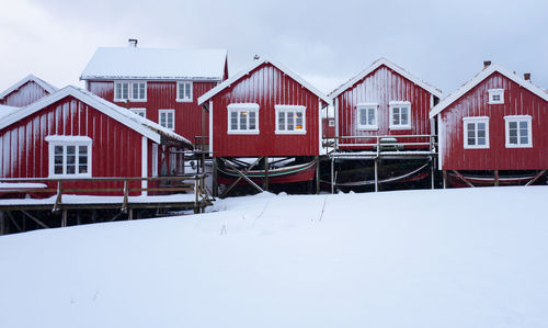 Snow covered houses by buildings in city against sky