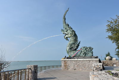 Statue by sea against sky